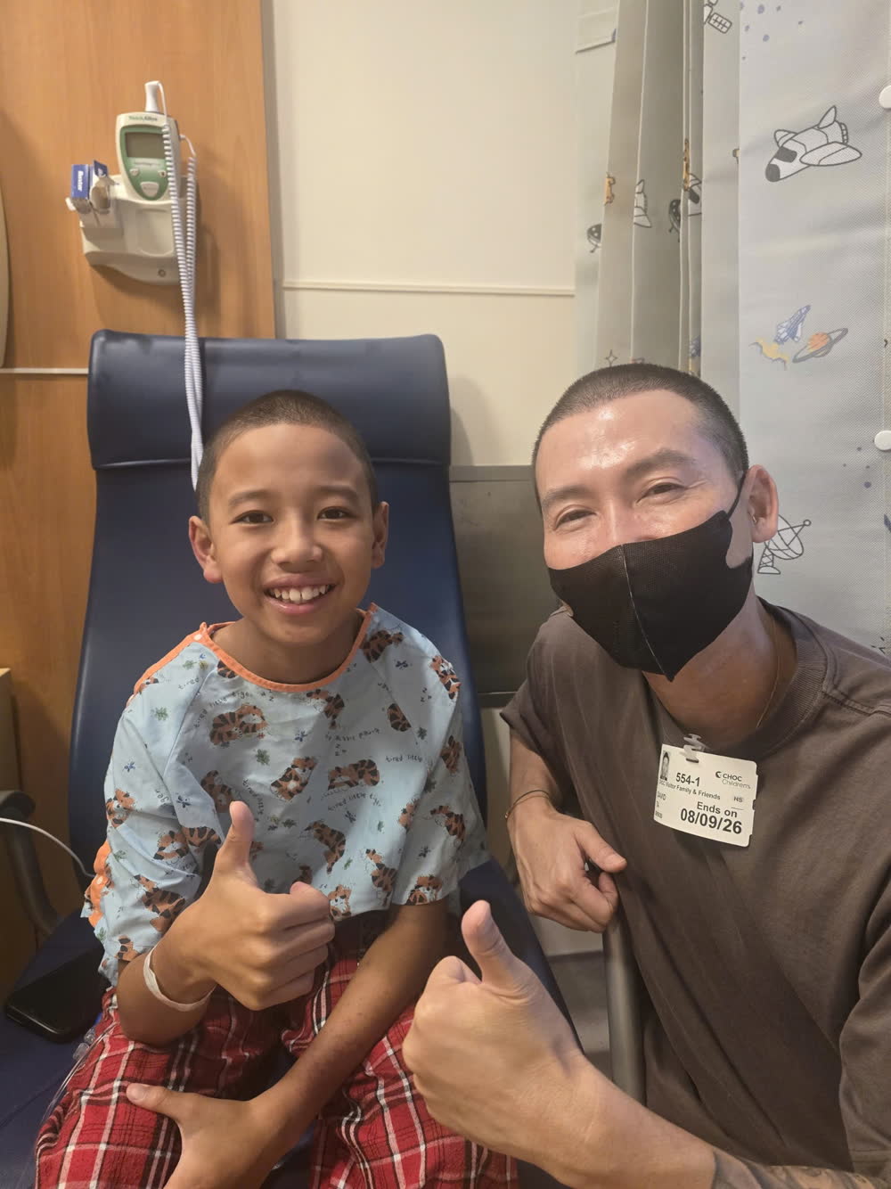 David Ta and Keegan side by side in the hospital, both giving a thumbs up.